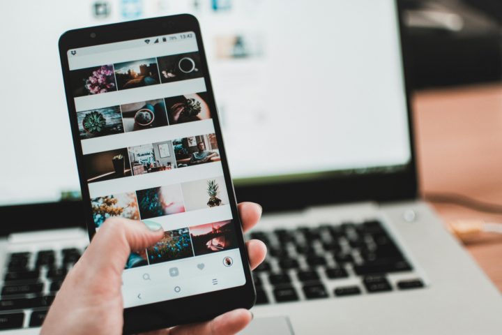 Auf dem Bild ist ein Smartphone im Vordergrund. Im Hintergrund ist ein Laptop zu sehen.